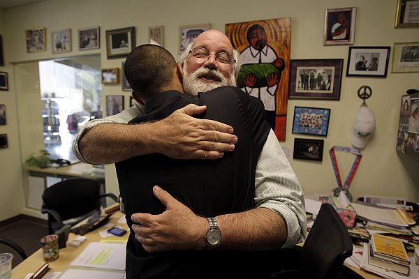 In a Friday, June 4, 2010 photo, Father Gregory Boyle hugs Robert Trejo, a former gang member, in his office at Homeboy Industries in Los Angeles. Organizations trying to prevent youngsters from joining gangs have been hit hard by the sour economy. Homeboy Industries, which employed ex-gang members as a way of keeping them off the street, had to fire more than 300 of its workers as donations and city subsidies plummeted. (AP Photo/Jae C. Hong)